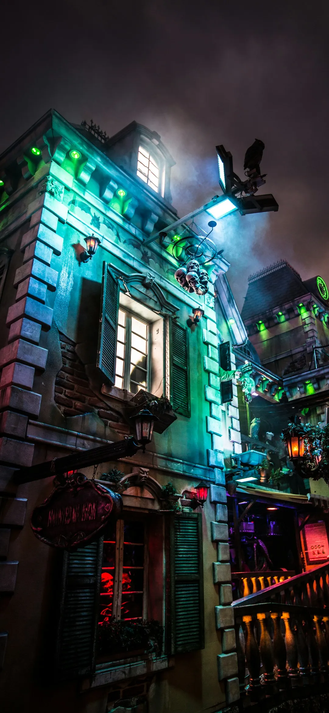 Haunted house lit in green and purple at night Halloween wallpaper