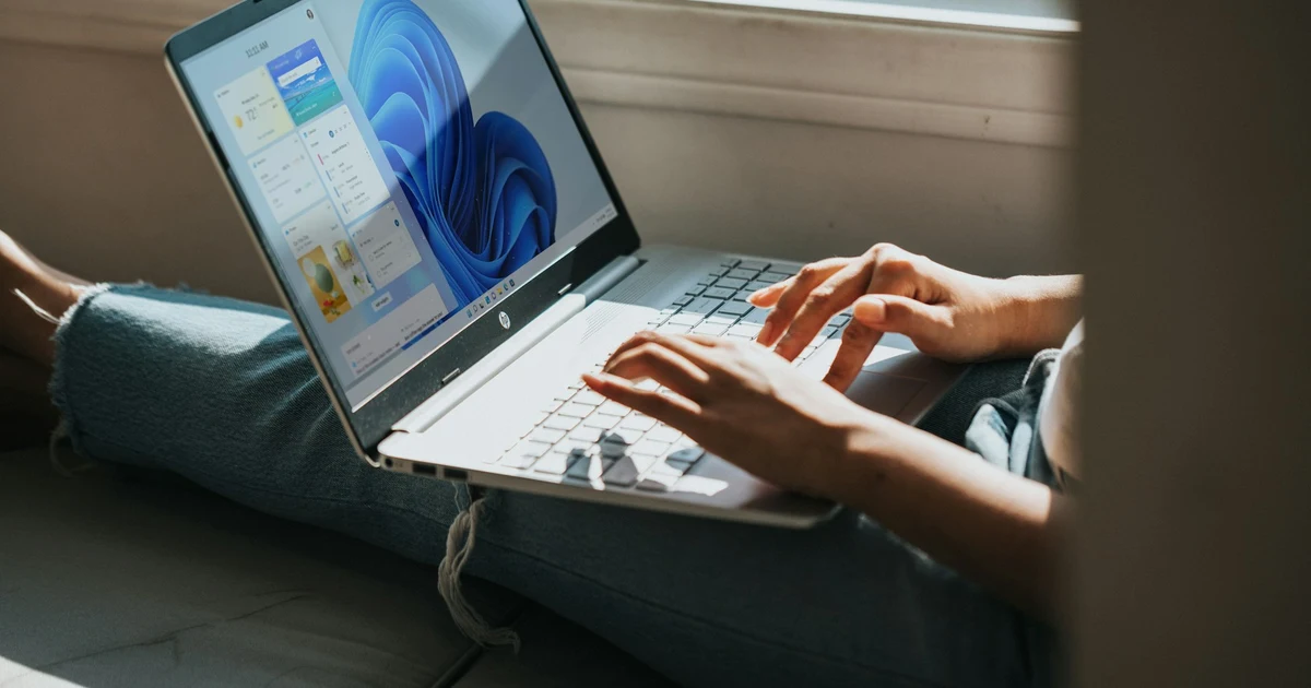 Person typing on a laptop showing the Windows 11 desktop
