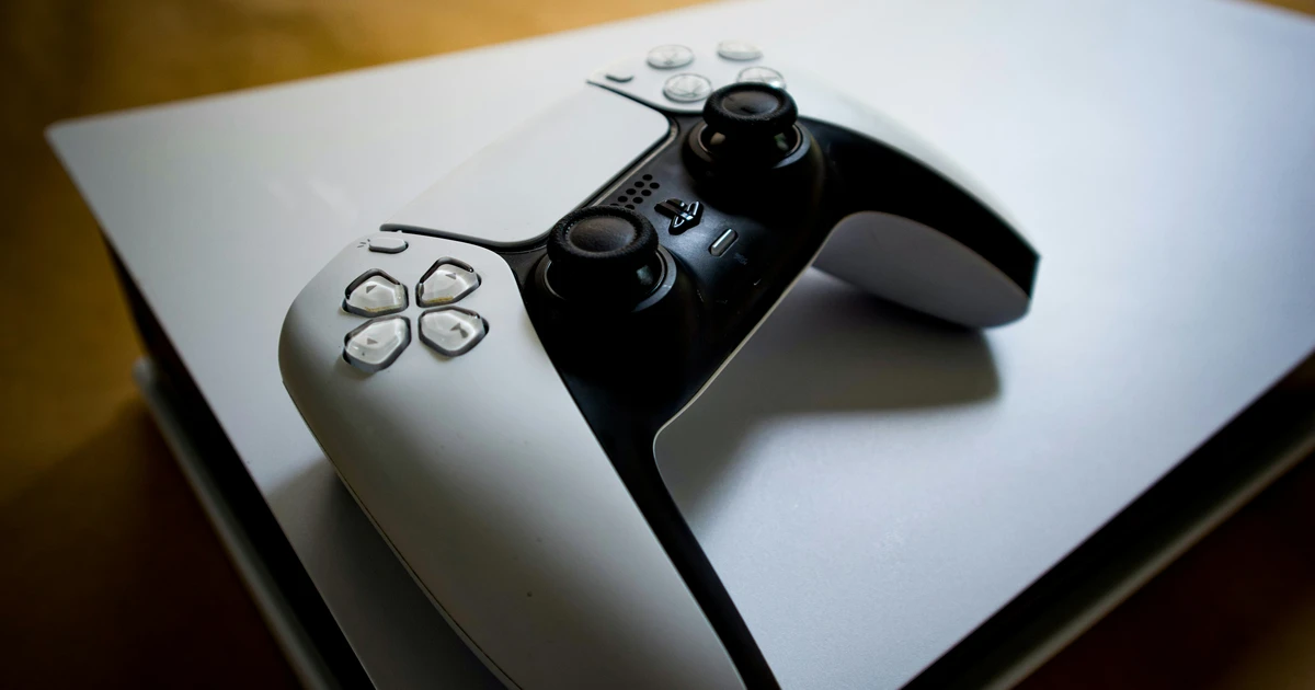 White PS5 DualSense controller resting on top of a PlayStation 5 console